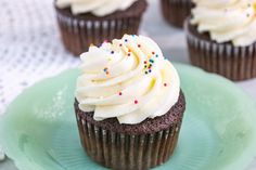 cupcakes with white frosting and sprinkles on a green plate