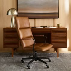 a brown leather office chair sitting in front of a desk with a lamp on it