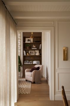 a living room filled with furniture and bookshelves next to a window covered in curtains