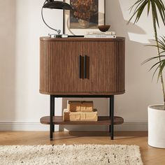 a wooden cabinet sitting on top of a hard wood floor next to a potted plant