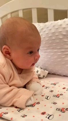 a baby laying on top of a bed next to pillows