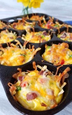 a muffin tin filled with breakfast food on top of a table next to a yellow flower