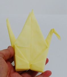 a hand holding a yellow origami bird