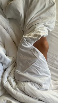 an unmade bed with white sheets and pillows