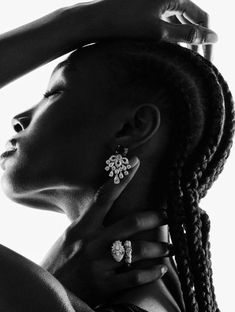 a woman with braids and earrings on her neck looking off to the side in black and white