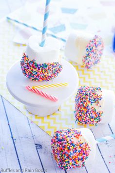 cake pops with sprinkles and a candle on a plate next to them