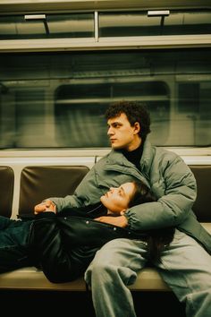 a man and woman sitting on a subway bench next to each other with their eyes closed