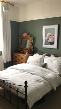 a bed with white linens and pillows in a green room next to a dresser