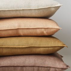 four pillows stacked on top of each other in different colors and sizes, with the same fabric