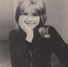 a black and white photo of a woman with her hand on her face, smiling