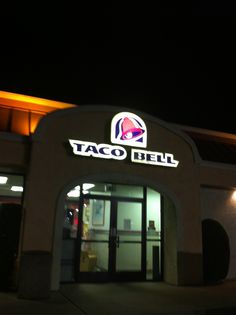 taco bell is lit up at night with its lights on