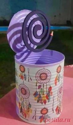 a tin can with a decorative design on it and a paper fan sticking out of the top