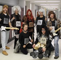 a group of people dressed in costumes posing for a photo with guitars and wigs