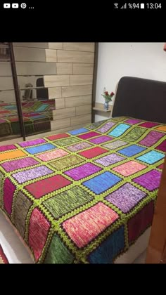 a multicolored crocheted bedspread on a bed in a room