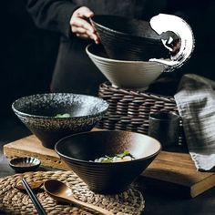 two black bowls and one white bowl with chopsticks