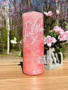 a vase with pink flowers and some kind of writing on it next to a candle that says girl mom