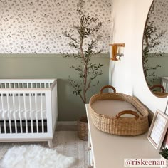 a baby's room with a crib, mirror and tree in the corner