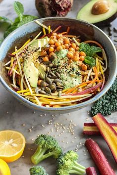 a bowl filled with broccoli, carrots and chickpeas next to sliced radishes