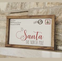 a wooden sign that says santa the north pole hanging on a stone fireplace mantel