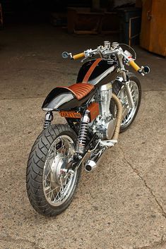 an orange and black motorcycle parked in a garage