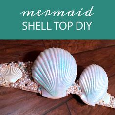 three seashells sitting on top of a wooden table with the words mermaid shell top diy