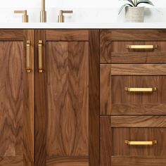 a bathroom vanity with wooden drawers and gold handles