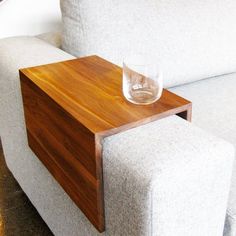 a glass sitting on top of a wooden table next to a white couch in a living room