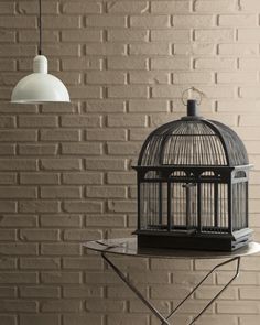 a birdcage sitting on top of a table next to a light hanging above it