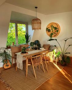 a dining room table and chairs with plants in the corner next to it on top of a rug