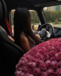 a woman sitting in the driver's seat of a car with flowers on the floor