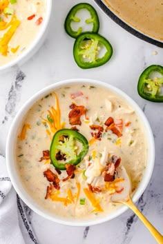 two bowls filled with soup and topped with cheese, jalapenos and bacon