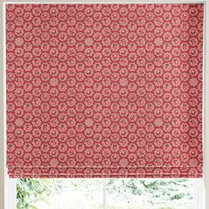 a red roman blind in front of a window with an ornate pattern on it,