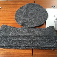 a pair of gray mitts sitting on top of a wooden table next to a laptop computer