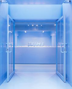 an empty blue room with white walls and lights on the ceiling is lit by recessed lighting