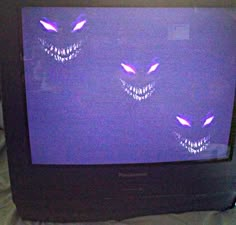 an old television with scary faces on it's screen and eyes drawn on the screen