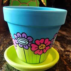 a blue flower pot sitting on top of a yellow saucer next to a green plate