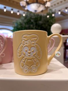 two coffee mugs sitting on top of a table in front of a ceiling light