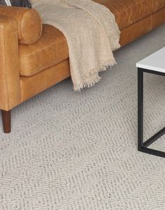 a living room with a couch, coffee table and rugs on the floor in front of it