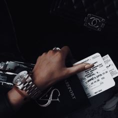 a person's hand with a watch on it and a passport in their other hand