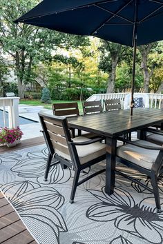 an outdoor dining table with chairs and umbrella