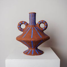 a brown and blue vase sitting on top of a white block