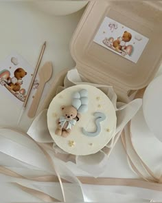 a baby's first birthday cake with a teddy bear on it and other items