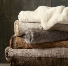 a pile of fur and blankets on top of each other in front of a wooden wall