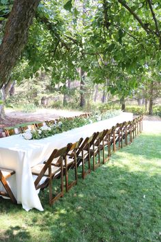 a long table is set up under the shade of a tree