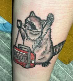 a raccoon with a radio tattoo on it's leg is holding a cord