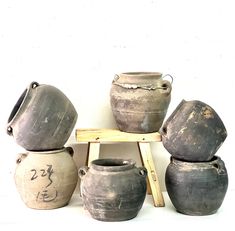 a group of pots sitting on top of a wooden stand next to each other in front of a white wall