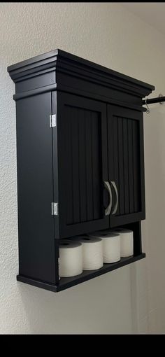 a black cabinet with four rolls of toilet paper on it