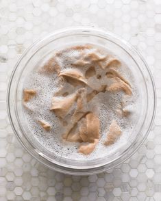 a bowl filled with sand on top of a white tiled counter