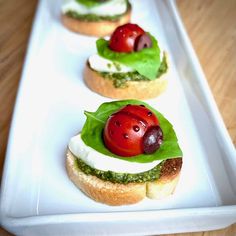 small sandwiches with tomatoes, cheese and pesto on them sitting on a white plate