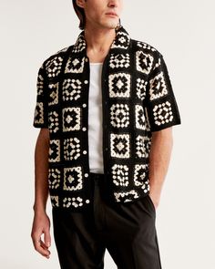 a man wearing a black and white knitted cardigan with circles on the front